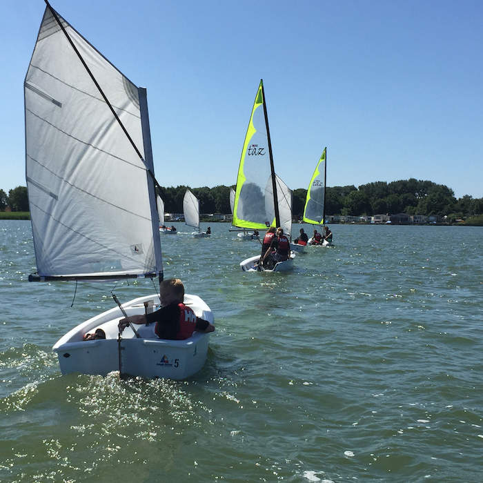 Kinderen varen in catamaranbootjes over de Amsterdamse meertjes op zomerkamp Amsterdam.