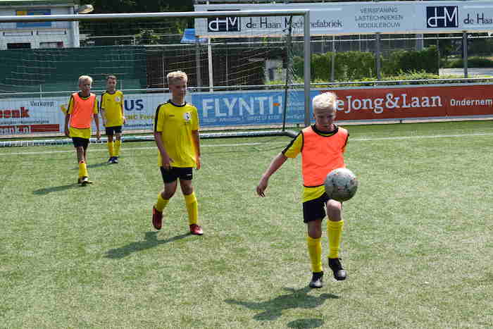 Jongens oefenen dribbel in de open lucht. 