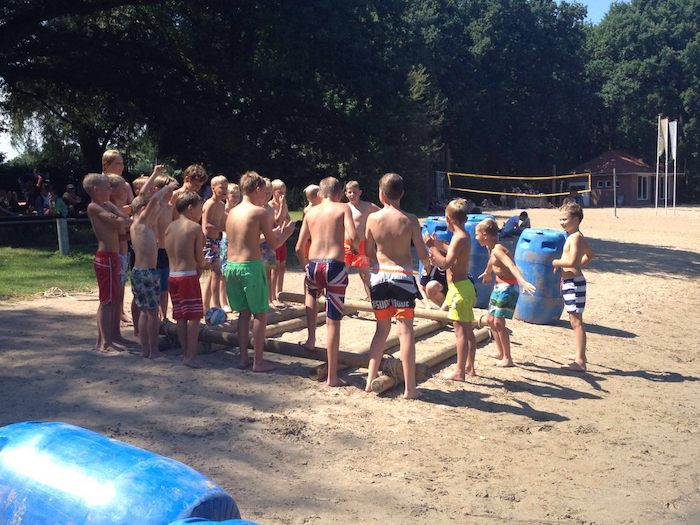 Jongens poseren lachend aan de rand van het zwembad. 