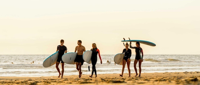 Groep wandelt over het strand tijdens surfkamp zomer
