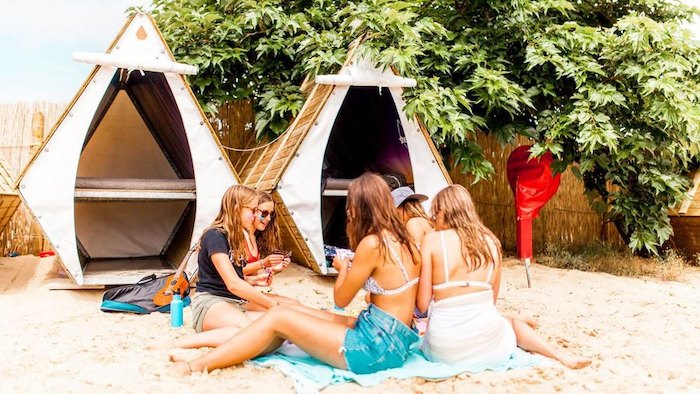 Meiden zitten aan tent tijdens een surfkamp zomer