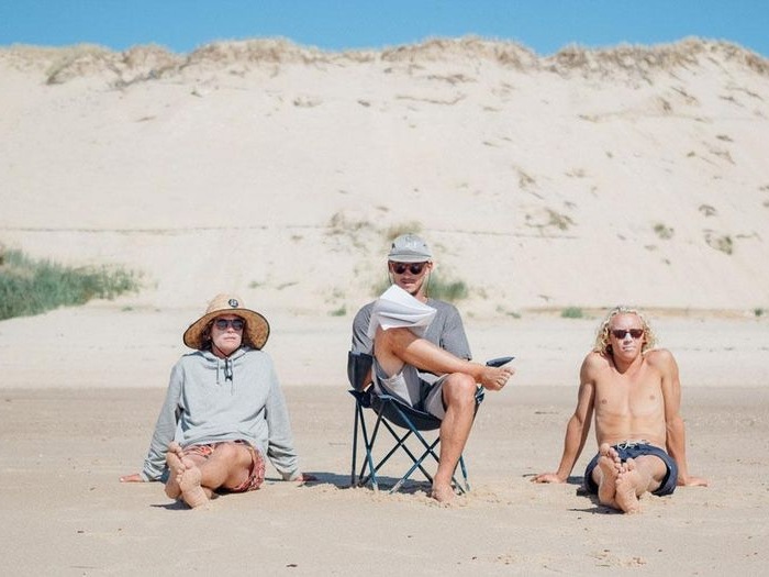 Op jongerenreis zitten jongeren naast elkaar in het zand.