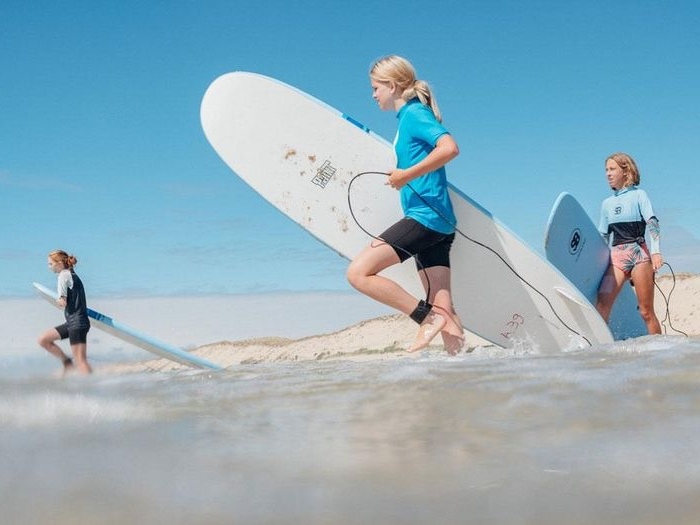 Jonge mensen wandelen met surfboards in de golven op jongereis. 