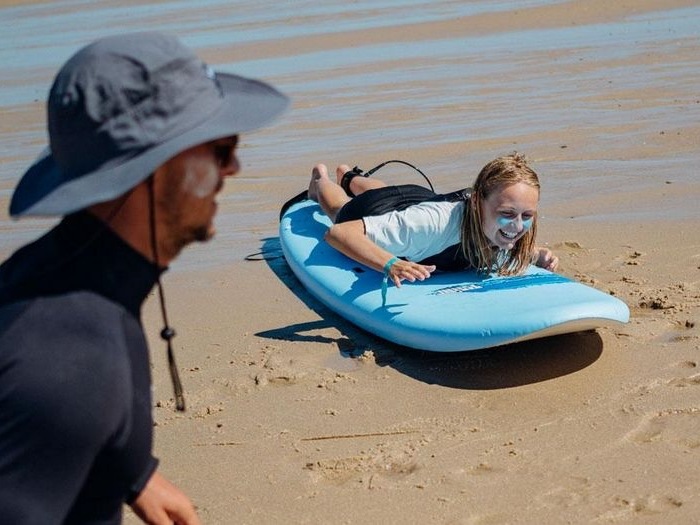 Tienermeisje ligt op plank tijdens surfkamp buitenland.