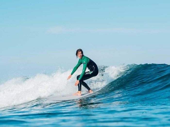 Jongen glijdt op board over de golven op surfkamp en kitesurfkamp Nederland