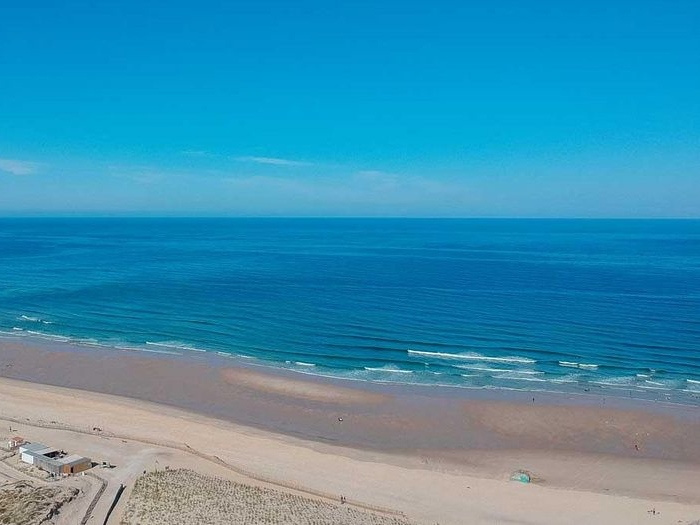 Blik op mooi strand en azuurblauwe zee tijdens surfkamp of kitesurfkamp Nederland.