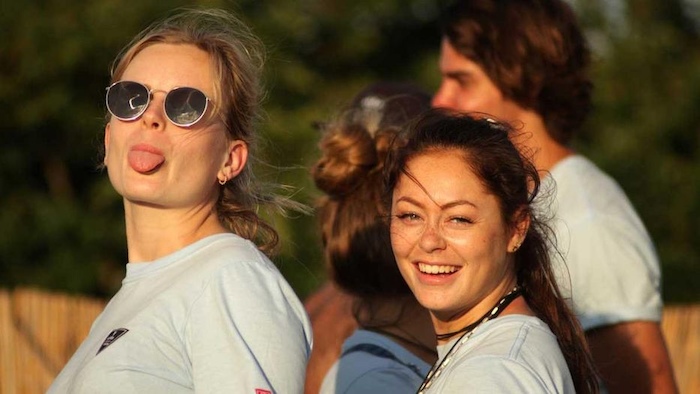 Meisjes lachen naar de camera op surfkamp.