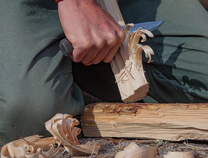 Gros plan sur une personne coupant du bois avec un couteau 