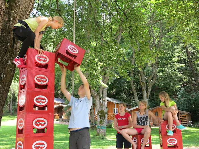 Kinder eines Sportcamps stapeln Bierkisten