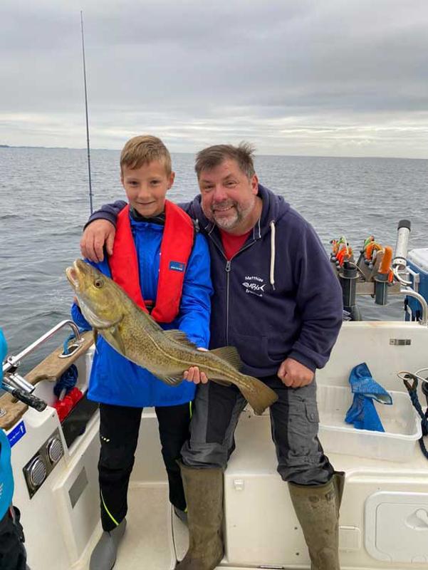 Ein Junge aus dem Angelcamp hält stolz einen großen Fisch in der Hand