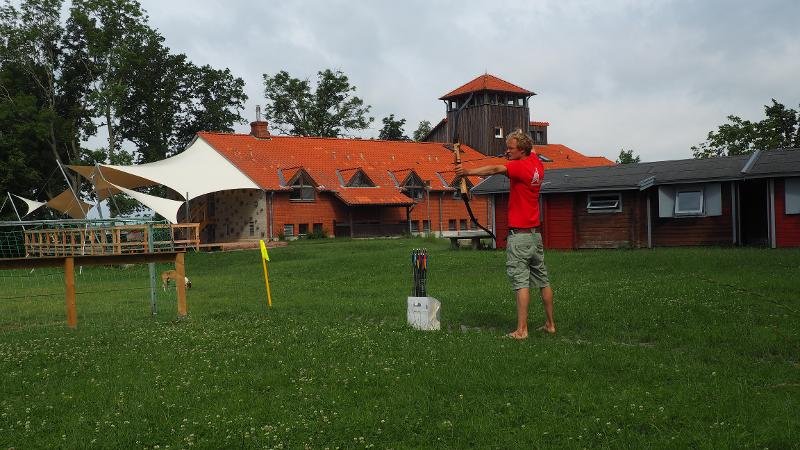 Ein Junge schießt bei Meerferien mit einem Bogen