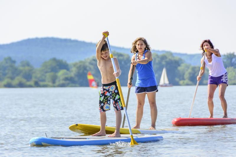 Drei Teilnehmer einer Jugendreise Griechenland fahren mit dem Stand-Up-Paddling Board
