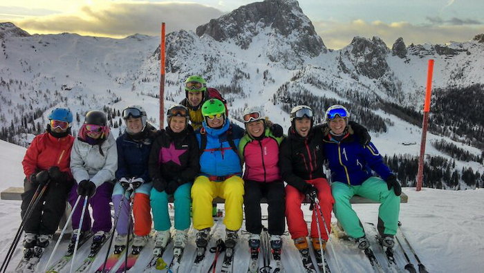 Teilnehmer eines Sportlagers sitzen im Schnee