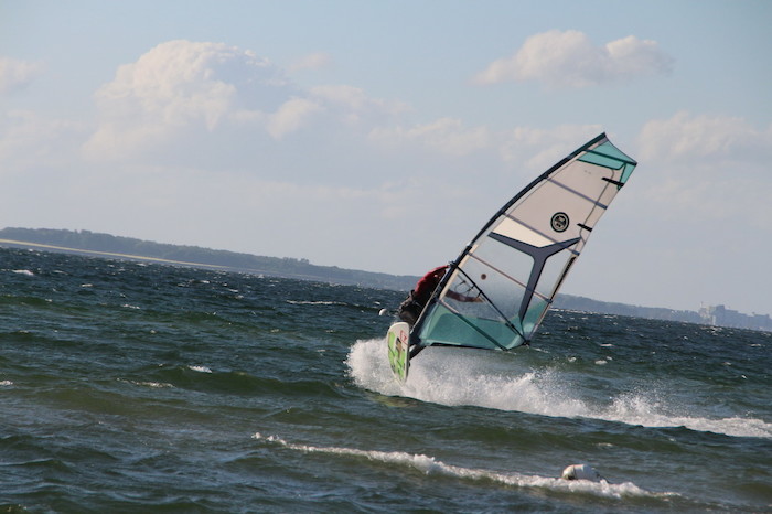 Eine Teilnehmerin vom Ferienprogramm Kiel ist am Windsurfen an der Küste 