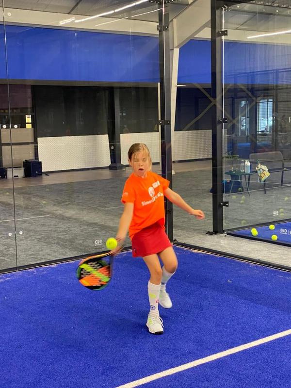 Ein Mädchen des Tennis-Camps schlägt einen Ball