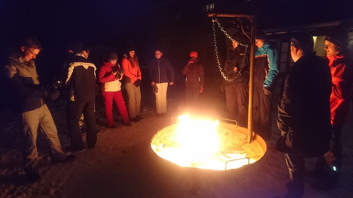 Teilnehmer einer Winterfreizeit sind am Lagerfeuer