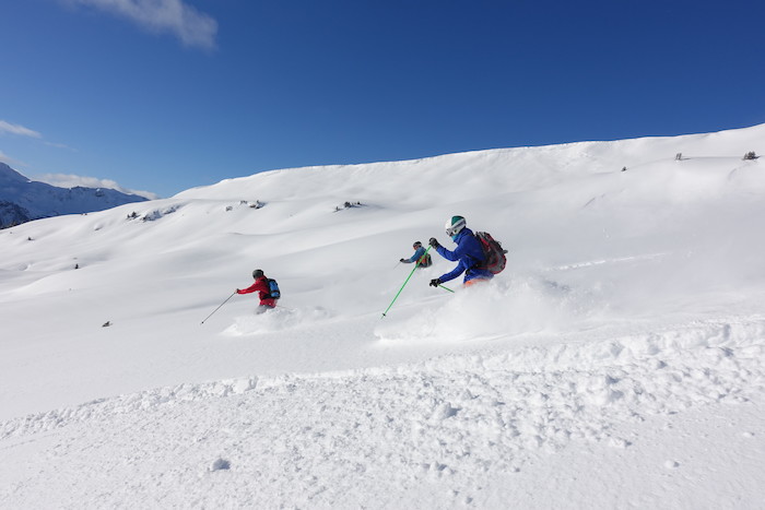 In einem Ski und Snowboardcamp fahren Teilnehmer durch den Tiefschnee