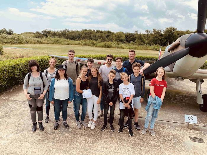 Die Jugendlichen der Sprachreisen Abiturvorbereitung machen ein Gruppenbild vor einem kleinen Flugzeug