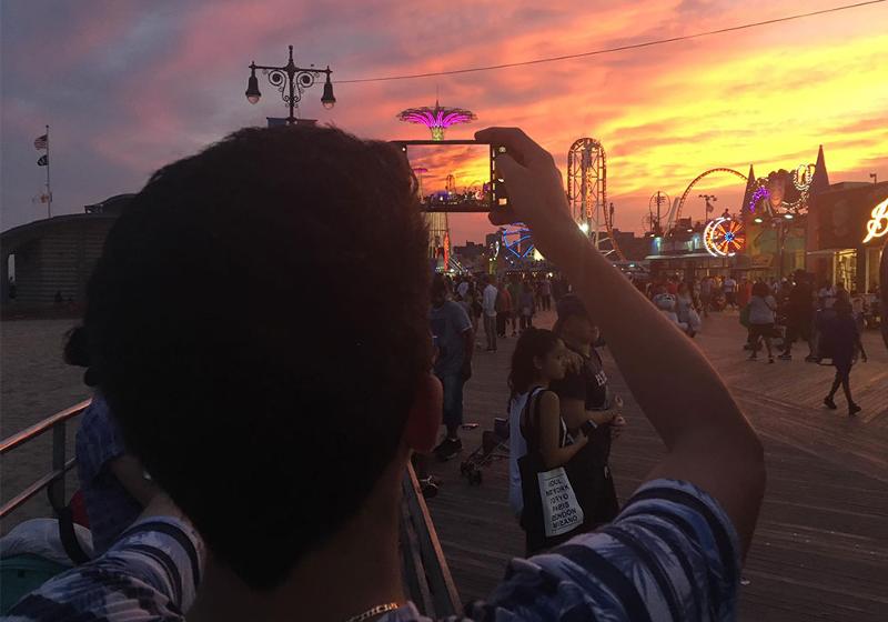 Ein Junge macht ein Foto von der Strandpromenade während des Sonnenuntergangs bei unseren Sprachreisen Amerika für Schüler