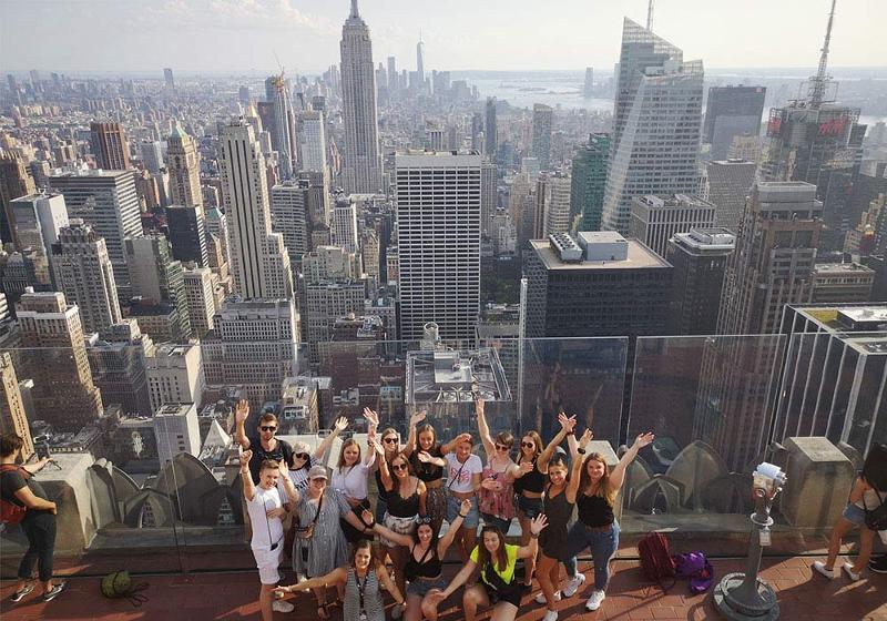  Eine Gruppe von Jugendlichen steht auf einem Hochaus in New York mit Ausblick über die Stadt für ein Gruppenfoto bei unseren Sprachreisen USA Sommerferien