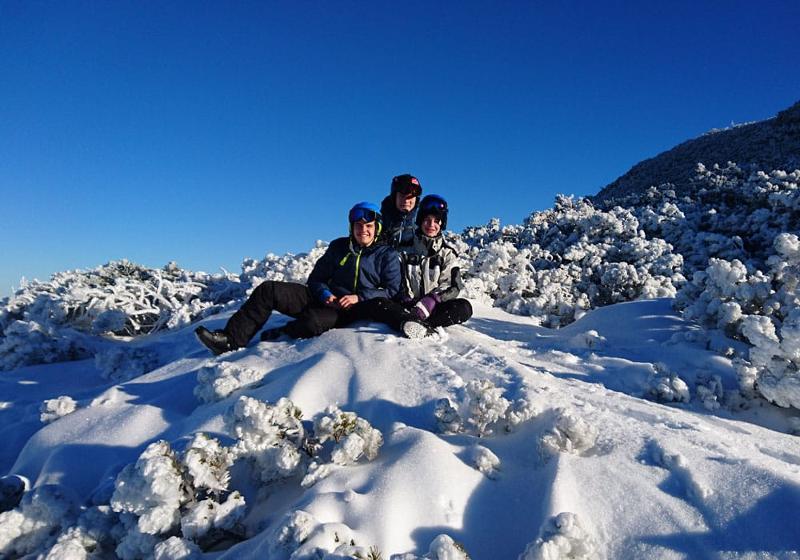 Teilnehmer einer Jugendreise ohne Eltern sitzen auf dem Schnee