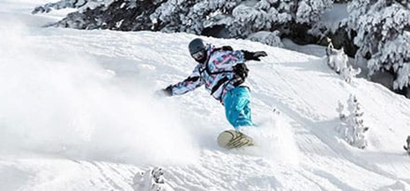 Teilnehmer einer Jugendreise ohne Eltern fährt Snowboard