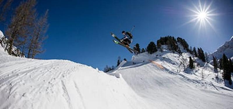 Teilnehmer einer Jugendreise ohne Eltern springt mit Ski
