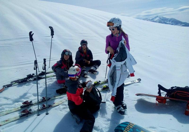 Teilnehmer einer Jugendreise ohne Eltern sitzen im Kreis im Schnee