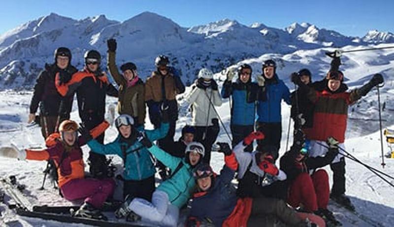 Teilnehmer einer Jugendreise ohne Eltern jubeln im Schnee