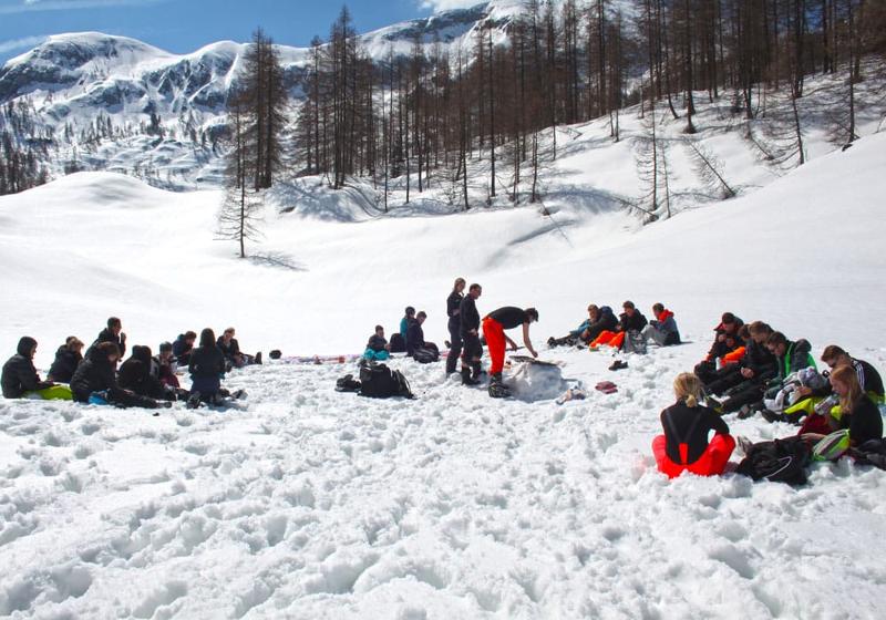Teilnehmer einer Jugendreise ohne Eltern machen Gruppenspiele im Schnee