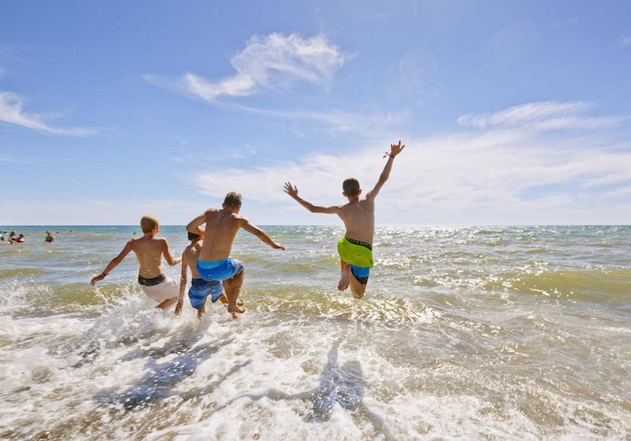 Teilnehmer einer Jugendreise ohne Eltern springen im Wasser