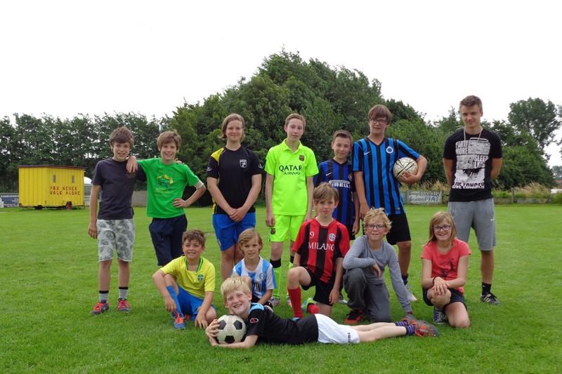 Jongens poseren op voetbalveld met bal