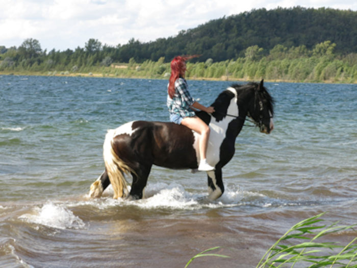 Ein Mädchen der Reiterferien für Kinder in Sachsen reitet durch den See