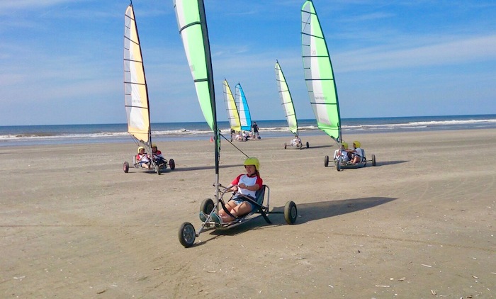 Kinder fahren im Sprachcamp NRW mit einem Kite-Buggy am Strand