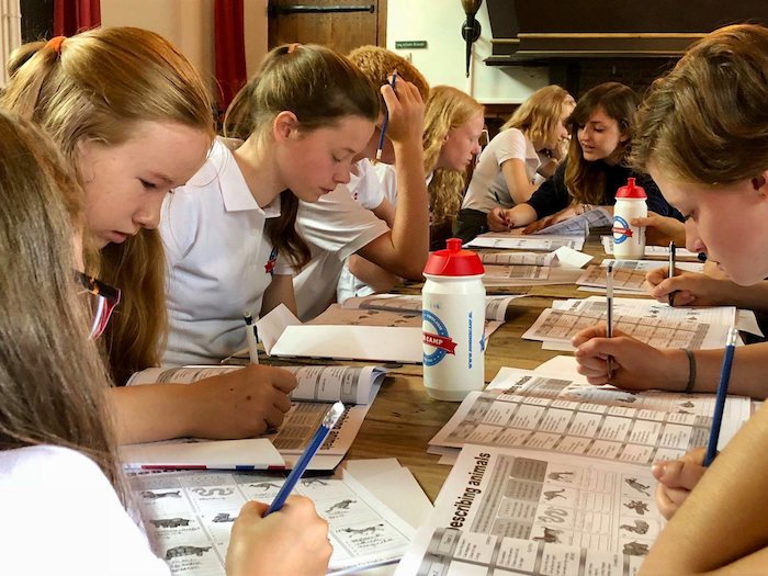 Kinder sitzen im Englischcamp NRW am Tisch und schreiben
