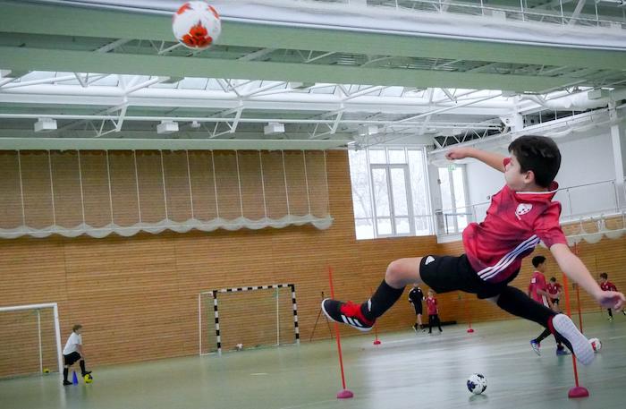Ein Kind macht gerade beim Fußballspielen in der Halle einen Seitfallzieher