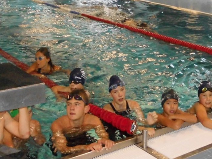 Die Kinder der Ferienbetreuung stehen am Beckenrand im Wasser