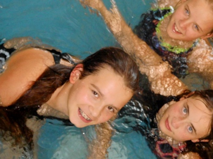 Mädchen lächeln während der Ferienbetreuung aus dem Wasser in die Kamera