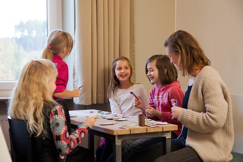 Kinder spielen mit Betreuerin Karten