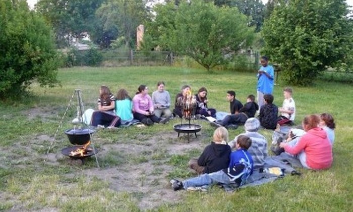 Teilnehmer eines Feriencamps für Kinder sitzen am Lagerfeuer