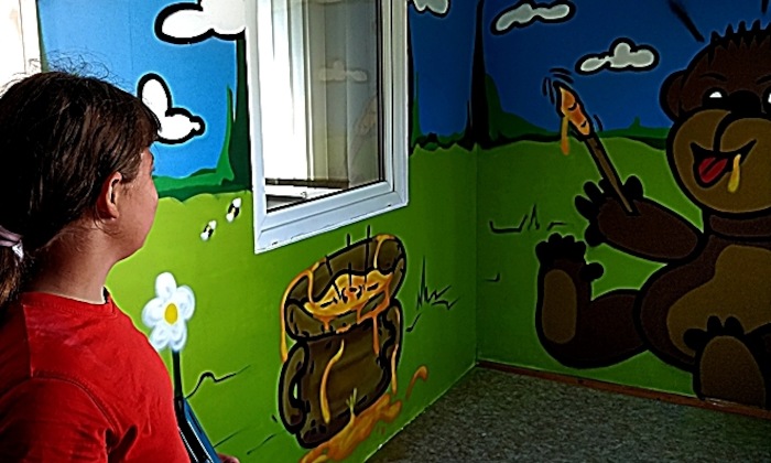 Teilnehmer eines Feriencamps für Kinder malen Wände an