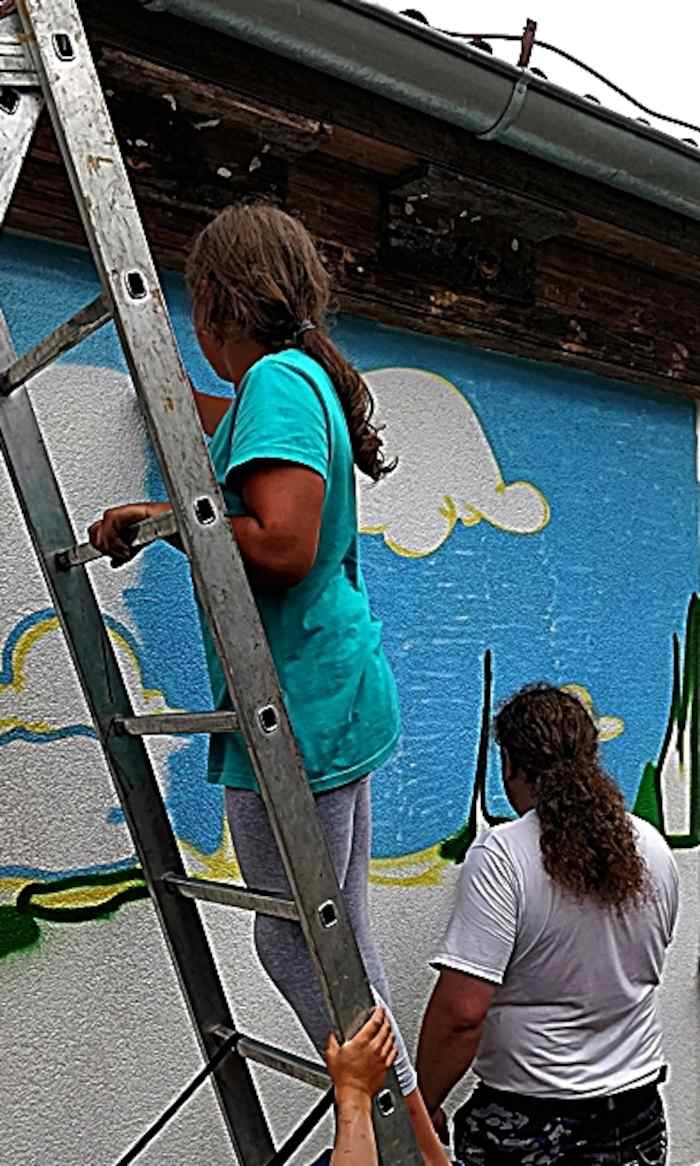 Teilnehmer eines Feriencamps für Kinder stehen auf der Leiter