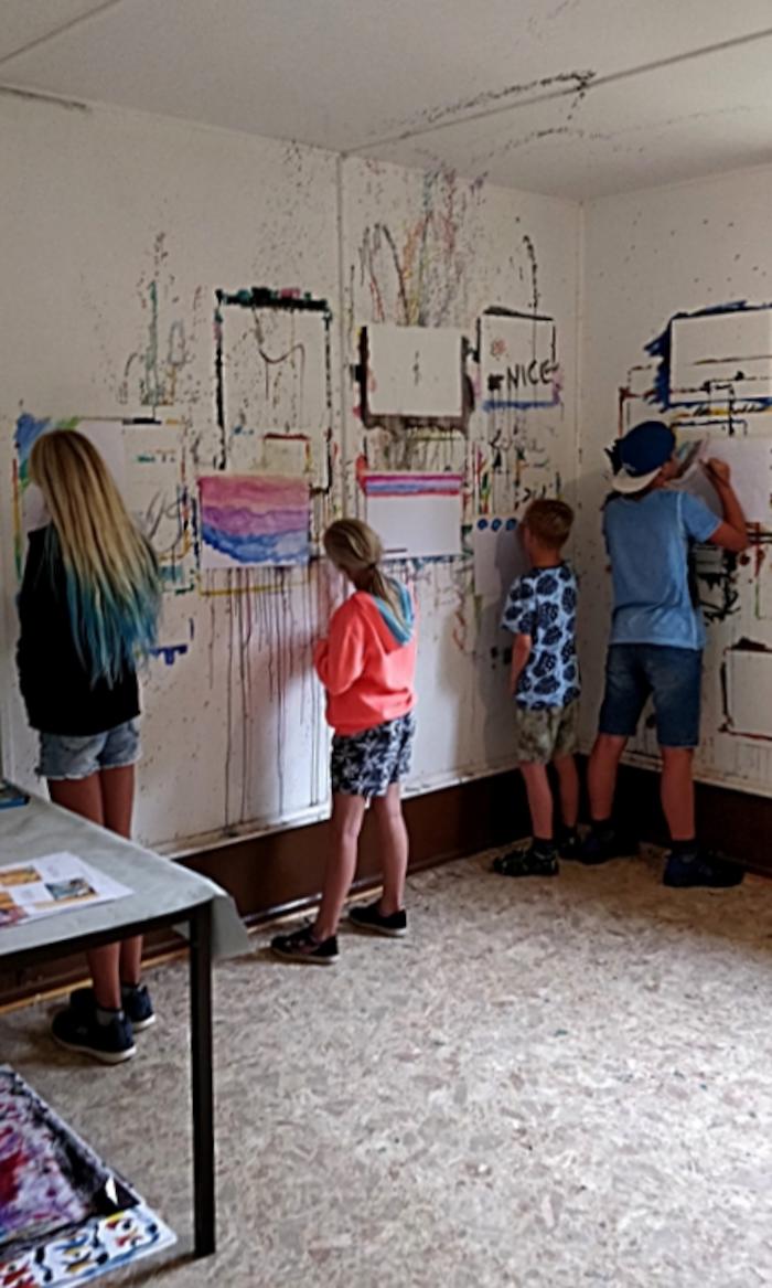 Teilnehmer eines Feriencamps für Kinder malen auf Papier