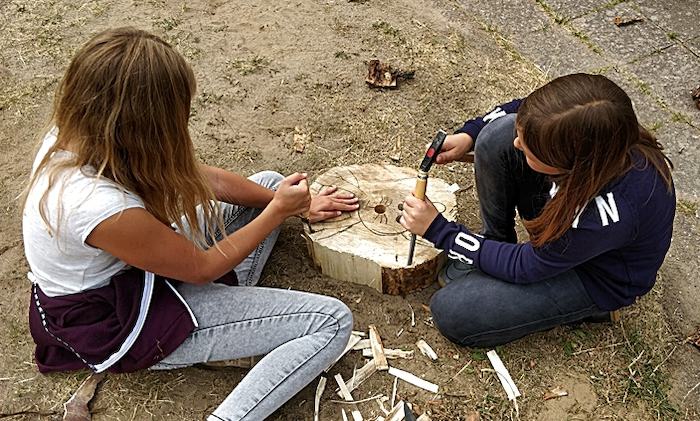 Teilnehmer eines Feriencamps für Kinder schnitzen