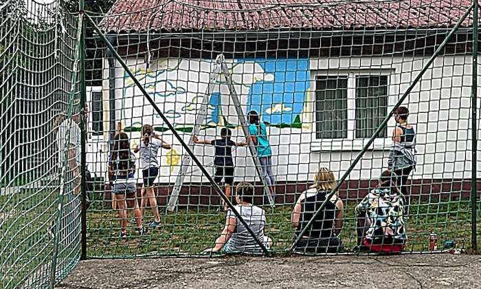 Teilnehmer eines Feriencamps für Kinder sind hinterm Tor