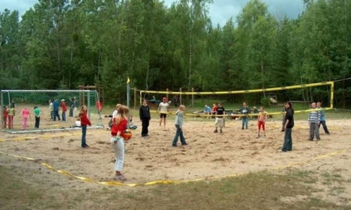 Auf dem Beachvolleyballfeld im Ferienlager Kutzowsee spielt eine Gruppe Kinder