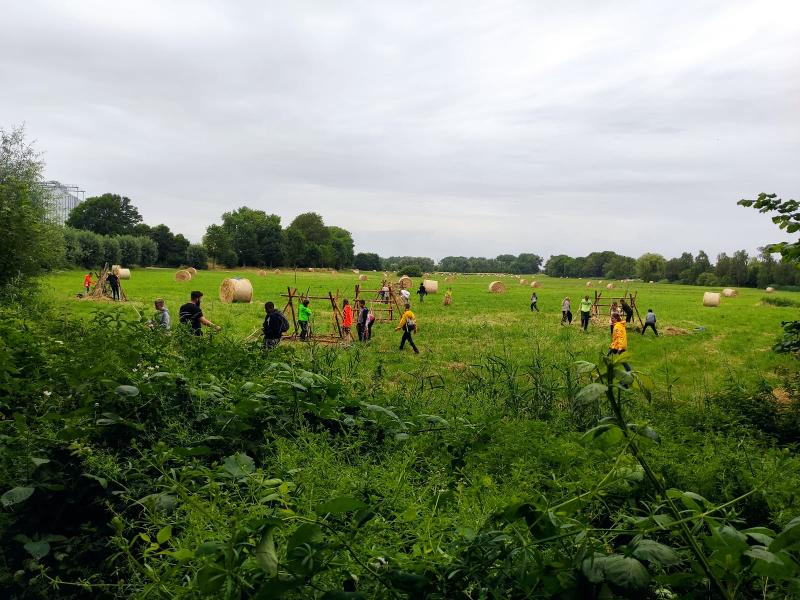 Kinder eines Feriencamps am Wasser laufen auf einem Feld