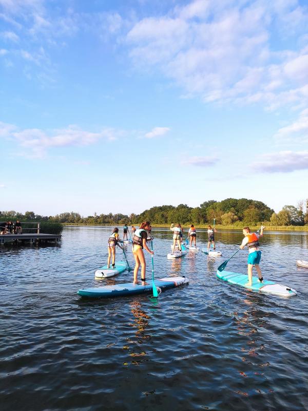 Kinder eines Feriencamps am Wasser fahren SUB