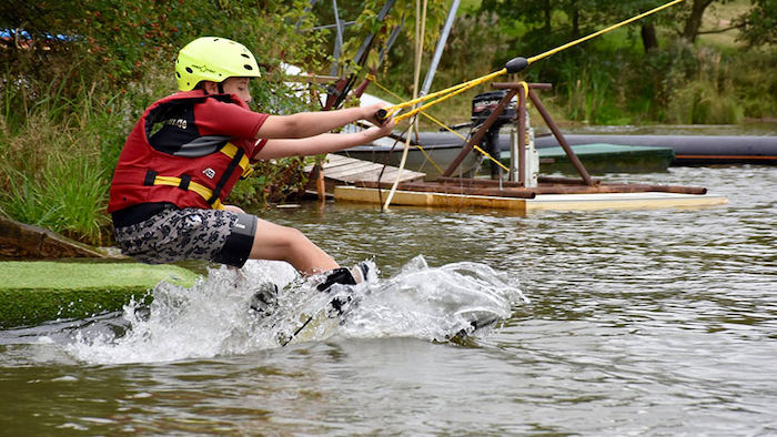 Ein Junge eines Wasserski Camps startet am See