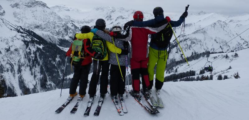 5 Jugendliche stehen im Wintercamp auf Skiern und am Hang